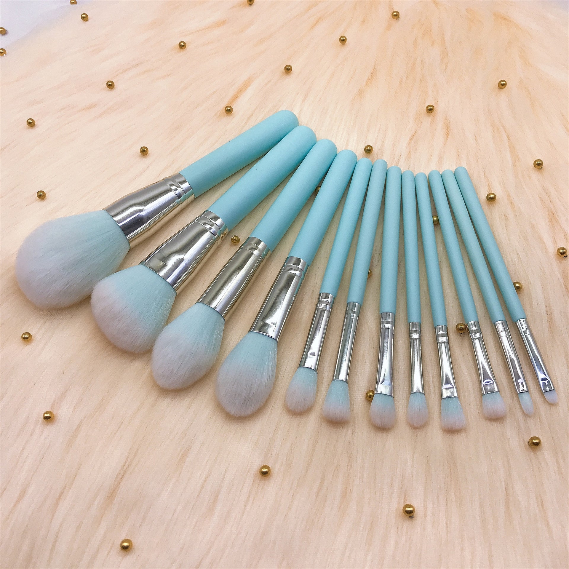 A set of 12 light blue wooden-handle makeup brushes, including small rainbow makeup brushes, powder brushes and eye brushes, as makeup tools.